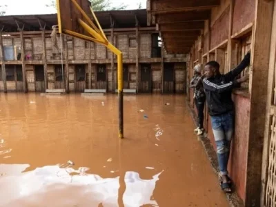 Warga di kawasan permukiman 'Mathare' menggunakan dinding untuk melintasi lapangan sekolah yang terendam banjir, menyusul hujan lebat di ibu kota Kenya, Nairobi. Foto : AFP
